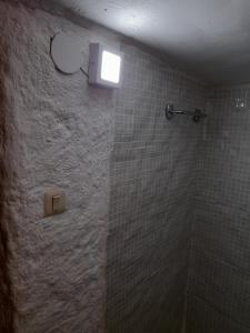 a bathroom with a tiled shower with a light on the wall at Casa cueva El Algarrobo in Guadix