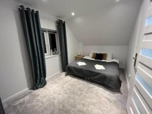 a bedroom with a black bed and a window at Mazurska Osada Domki in Rydzewo