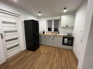 a kitchen with a black refrigerator and a wooden floor at Mazurska Osada Domki in Rydzewo