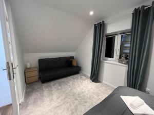 a bedroom with a black couch and a window at Mazurska Osada Domki in Rydzewo
