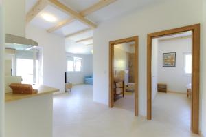 una sala de estar abierta con paredes blancas y vigas de madera. en Apartmani Porat Sali, en Sali