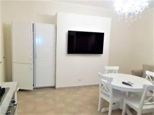 a white dining room with a table and a tv on a wall at Il Giardino degli aranci in Pisciotta