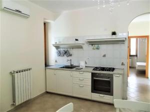 a white kitchen with a stove and a sink at Il Giardino degli aranci in Pisciotta