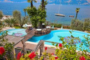 una grande piscina accanto a un grande bacino d'acqua di Belfiore Park Hotel****S a Brenzone sul Garda