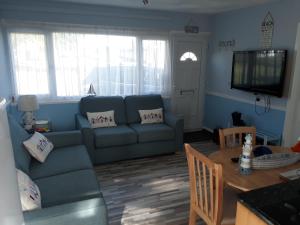 a living room with a blue couch and a table at Holiday at Hemsby in Hemsby