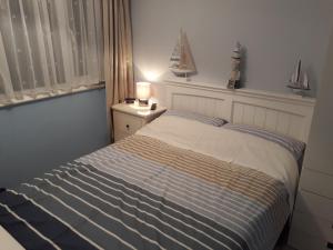 a bedroom with a bed and a lamp on a night stand at Holiday at Hemsby in Hemsby