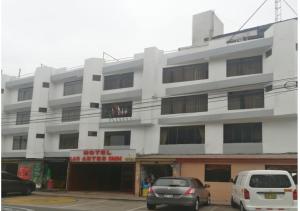 un edificio blanco con coches estacionados frente a él en LAS ARTES INN en Lima