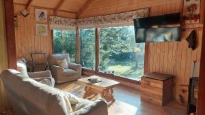 una sala de estar con 2 sillas y TV en una cabina en Casa Camino al Volcán, en Pucón