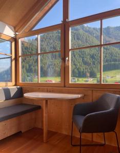 a room with a table and a chair and windows at Apartment Cesa Collina in Ortisei