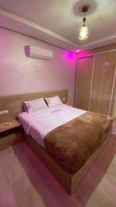um quarto com uma cama com luzes cor-de-rosa em Luxueux Condo - Down town em Marrakech