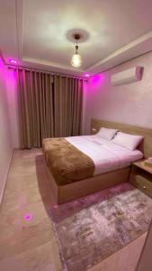 um quarto com uma cama com luzes cor-de-rosa em Luxueux Condo - Down town em Marrakech