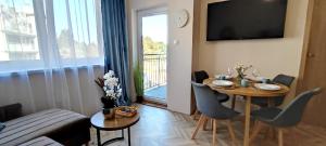 a living room with a table with chairs and a television at Apartamenty Przy Wydmie Dębina in Debina