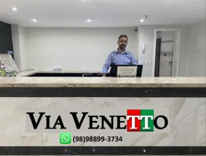un hombre parado en un escritorio con un portátil en Via Venetto - Vista Mar, en Fortaleza