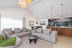 a living room with two couches and a kitchen at The Green House - Luxury Eco Escape in Martinborough 