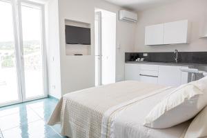 a white bedroom with a bed and a kitchen at Relais Solis in Ponza