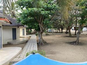 een blauw zwembad voor een huis met bomen bij Hotel Bel Azur Grand-Popo in Nicouécodji