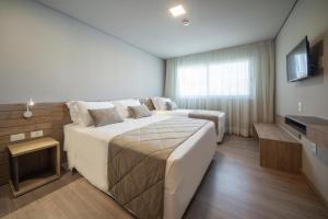 ein Hotelzimmer mit zwei Betten und einem Fernseher in der Unterkunft Laghetto Resort Golden Gramado - 46 m2 - Vista para o Vale in Gramado + 33 Fotos