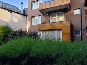 a building with a balcony and some green grass at Alegra Centro in San Martín de los Andes