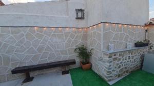 a stone wall with a bench and lights on it at El Patio Grande in Menasalbas