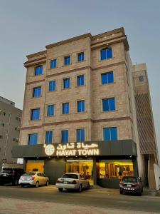 a large building with cars parked in front of it at حياة تاون 3 in Umm Lujj