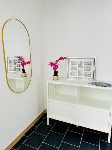 uma cómoda branca com um espelho e flores em Urban Sejour - Hyper Center em Liège
