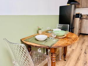 een houten tafel met kommen en wijnglazen erop bij Le p'tit canaulais - Logement entier - rez de jardin - paisible in Lacanau