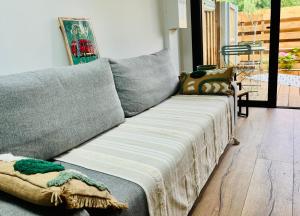 een grijze bank met een deken erop in de woonkamer bij Le p'tit canaulais - Logement entier - rez de jardin - paisible in Lacanau