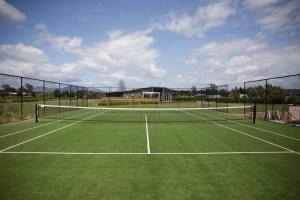 a tennis court with a net on a green court at Black Barn Modern: Luxe Martinborough Escape in Martinborough 