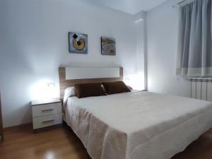 a white bedroom with a bed and a nightstand with a bed sidx sidx sidx at Apartamento Estrella de Teruel in Teruel