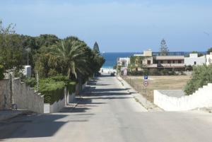 an empty road with palm trees on the side at Casa Vacanza Azzurra in San Vito lo Capo
