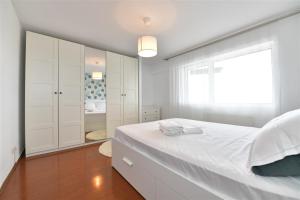 a white bedroom with a large bed and a window at Apartament LUX 1 Mai Pod in Bucharest