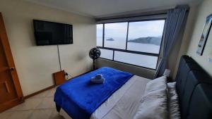 a bedroom with a bed with a blue blanket and a large window at El Peñon del Rodadero - Apto 1303A in Santa Marta