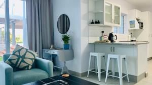 sala de estar con sofá azul y cocina en Stay in Style, en Durban
