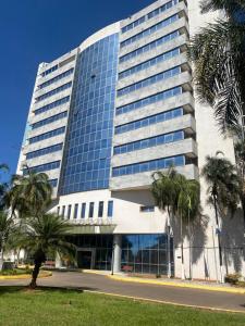 a large building with palm trees in front of it at Promoção - Flat em Brasília in Brasilia