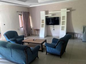 ein Wohnzimmer mit Stühlen, einem Tisch und einem TV in der Unterkunft Hotel Bel Azur Grand-Popo in Nicouécodji