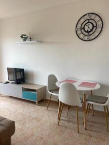 a living room with a table and chairs and a clock at Уютные апартаменты с боковым видом на море in Torrevieja