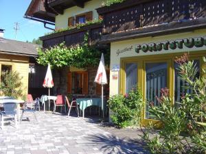a restaurant with tables and chairs in front of a building at Gasthof Forststube in Velden am Wörthersee