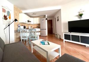 een woonkamer met een bank, een tv en een tafel bij Casa Teahupoo in Cotillo +8 foto's