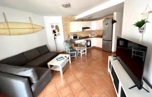 a living room with a couch and a kitchen at Casa Teahupoo in El Cotillo