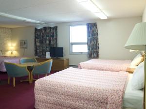 um quarto de hotel com duas camas e uma mesa e uma janela em Blue Bird Hotel em Melfort