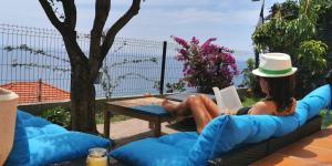 una mujer sentada en un sofá leyendo un libro en Vue magnifique, piscine privée chauffée et sauna à 10min de Monaco, en Roquebrune-Cap-Martin