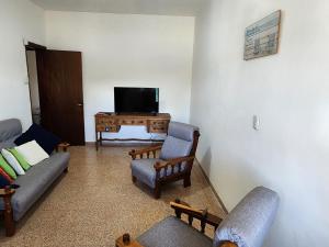ein Wohnzimmer mit Sofas, einem TV und einem Tisch in der Unterkunft Hermosa vista in Colonia del Sacramento