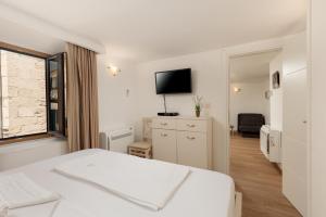 een witte slaapkamer met een bed en een televisie bij Apartment Amigo Old Town Kotor in Kotor