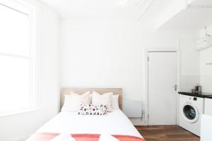 a white bedroom with a bed and a washing machine at Lovely Studio Flats in Hackney in London