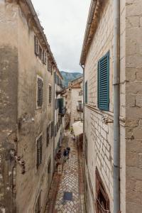 an alley with two people sitting in an alley between two buildings at Apartment Amigo Old Town Kotor in Kotor
