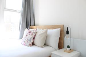 a bedroom with a bed with white pillows and a window at Lovely Studio Flats in Hackney in London