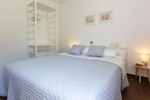 a white bed with blue pillows in a bedroom at SunSpot Apartment - beautiful view with big garden, free parking, central in Dubrovnik
