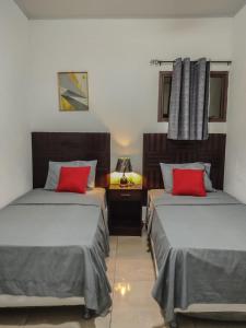 エステリにあるEste Hotelの赤い枕付きのベッド2台が備わる客室です。