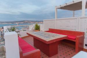 a red bench and table on a balcony with a view at Dar Louban House in Tangier Kasbah in Tangier