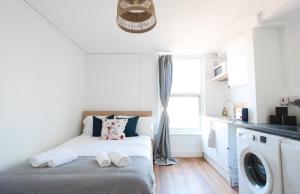 a small bedroom with a bed and a washing machine at Lovely Studio Flats in Hackney in London